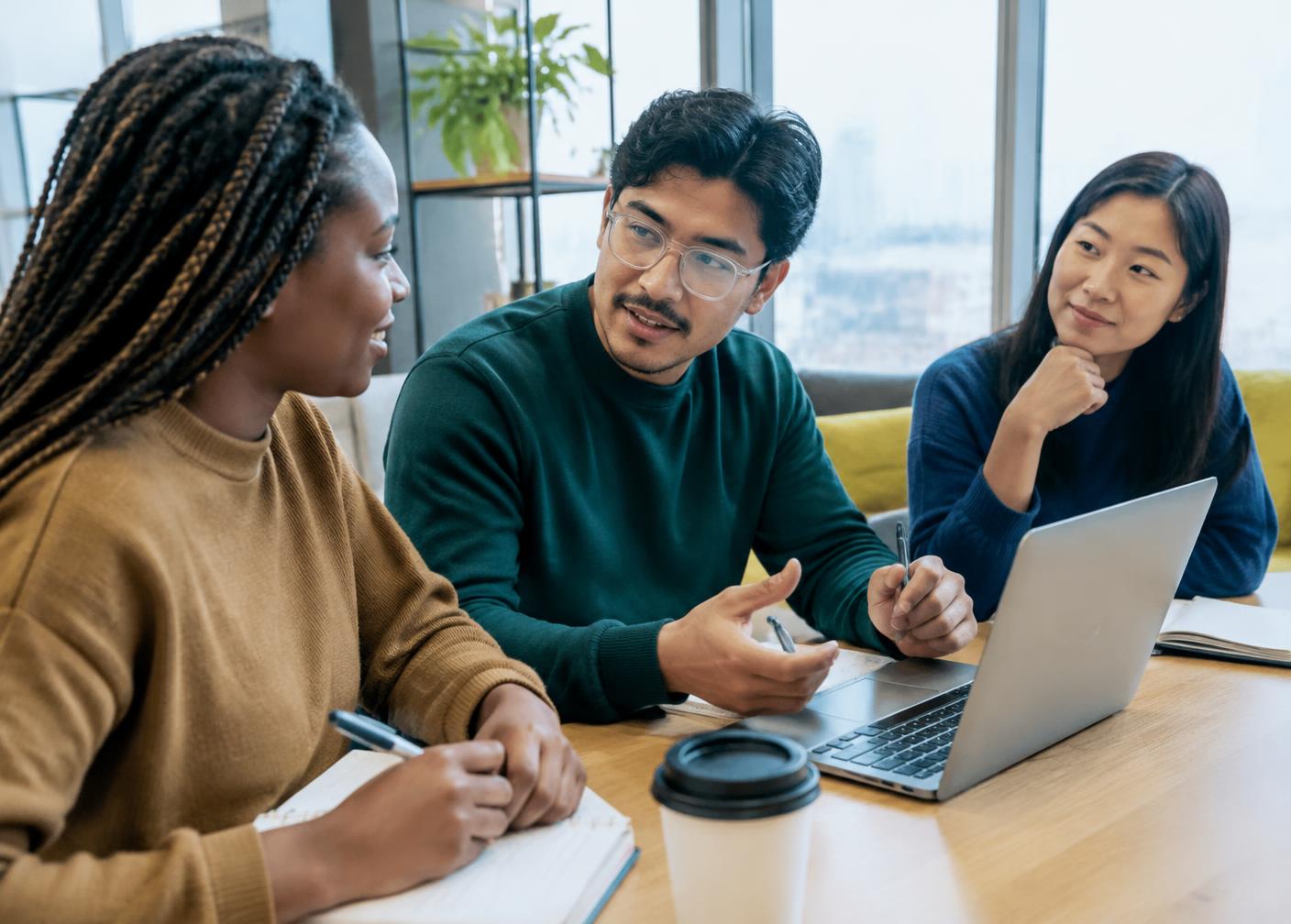 A mentor talking with two young interns at a table